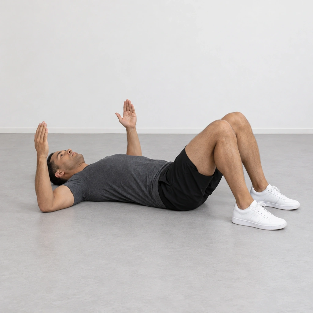 A man lying on his back on the floor with his knees bent, his feet flat, his upper arms and elbows on the floor and his forearms pointing up.