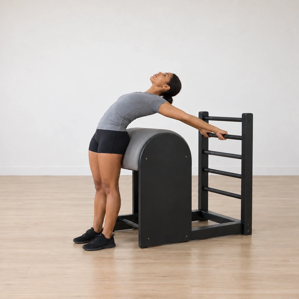 She is rounding back over the barrel, arms reaching up and back toward the top rung.