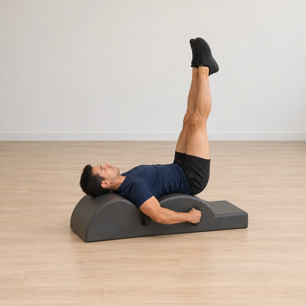He lies supine with his head toward the barrel end of the spine corrector, both hands holding the handles with the elbows worked wide, neck long, legs extended together.