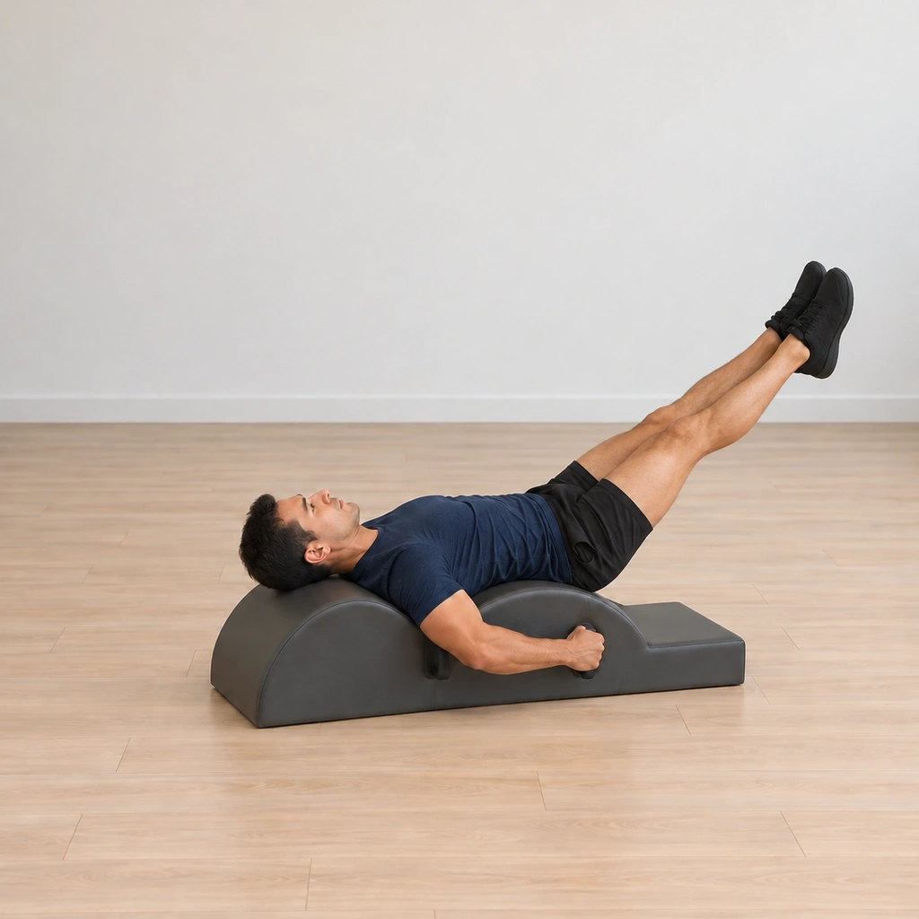 His legs return together lowering with control toward the mat, his head toward the barrel, elbows wide and hands on the handles.