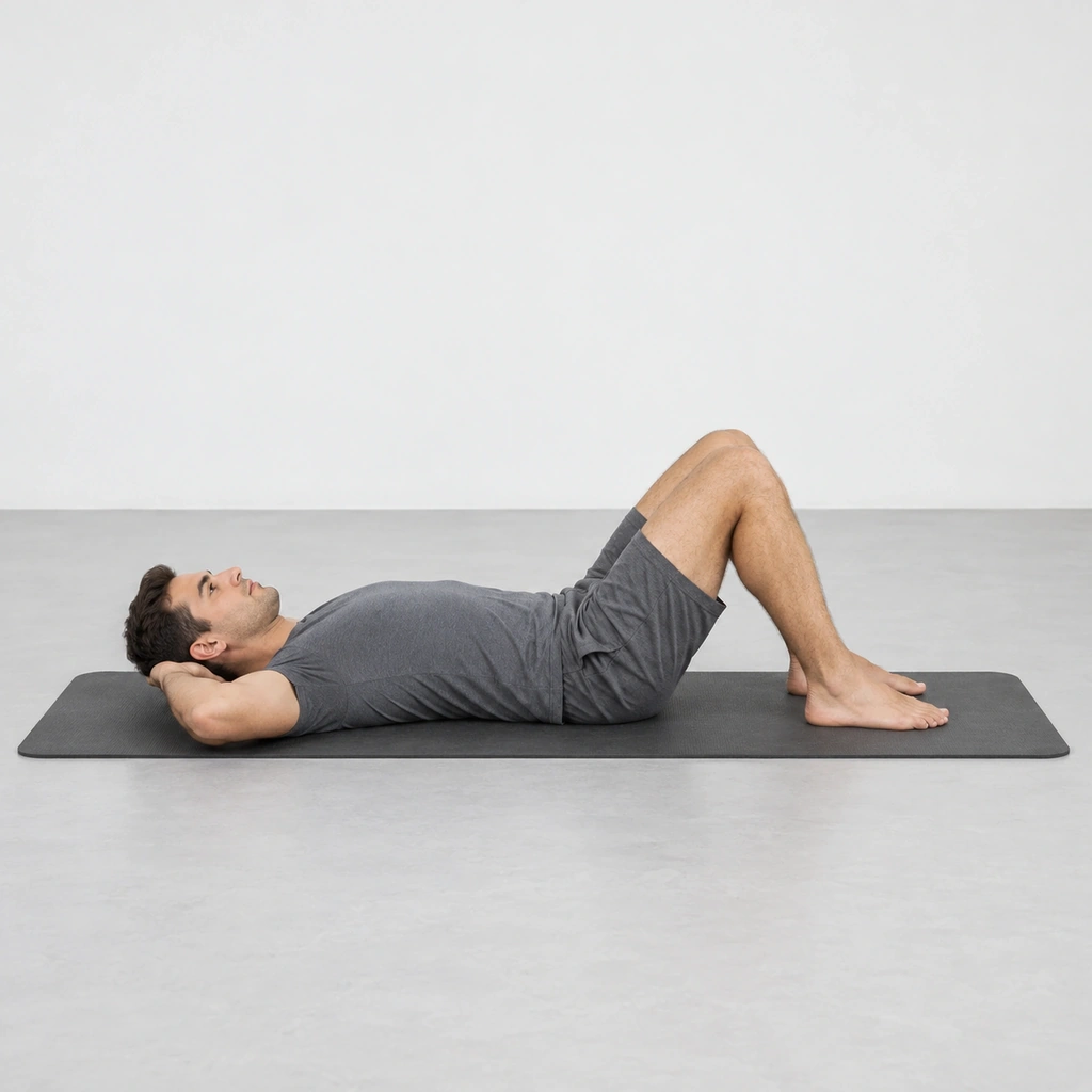Man lying on his back on a mat with his knees bent, his feet flat and his hands behind his head.