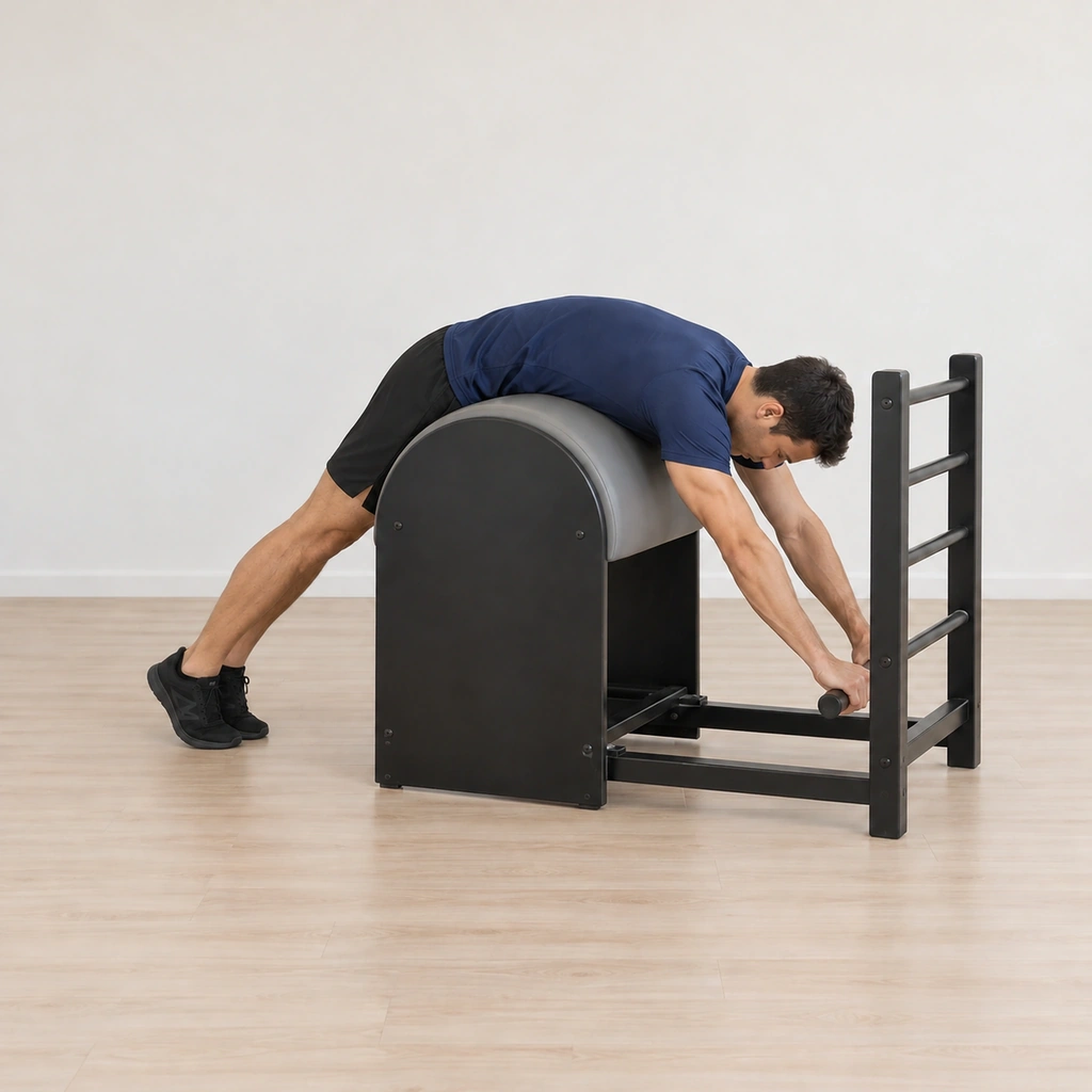 His legs lower with control back to the long reaching drape over the barrel, his hands still on the rung and his hips on the apex.