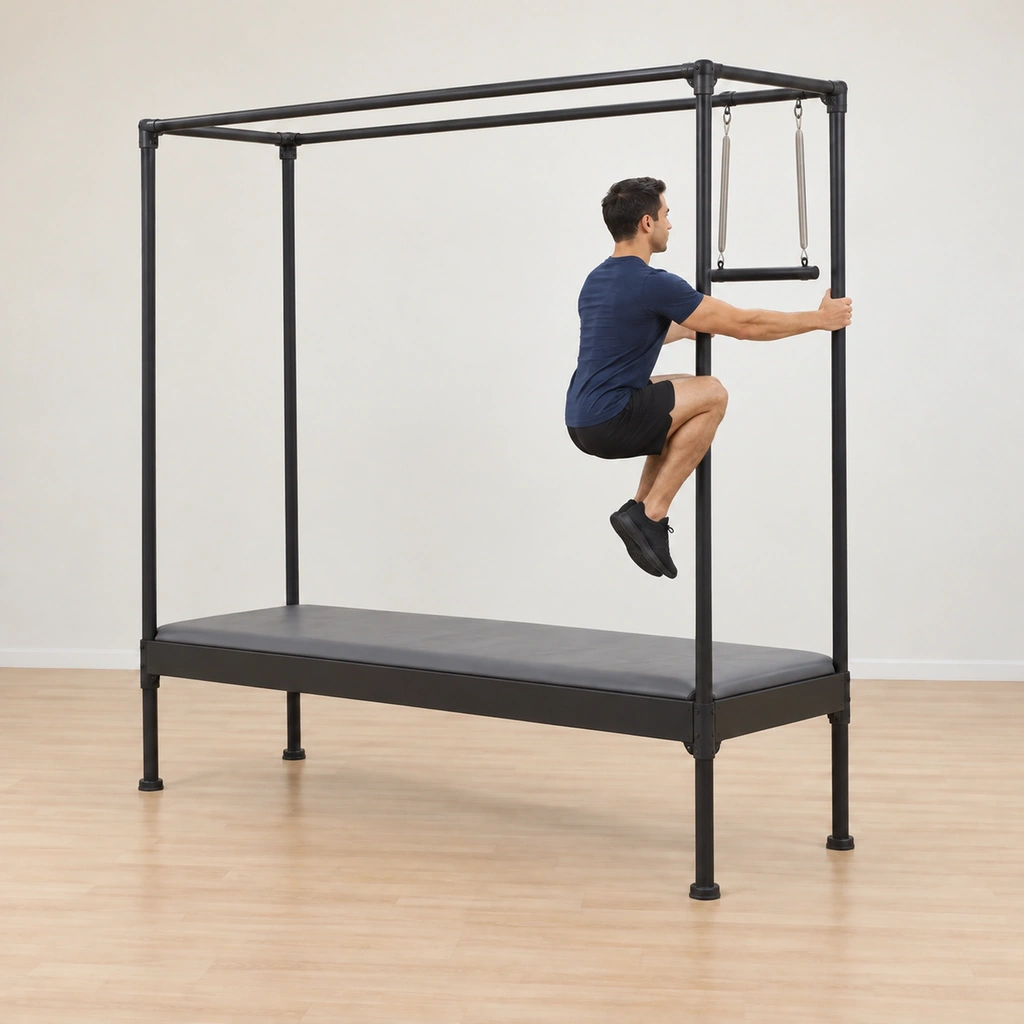 His body has folded back into the upside-down elephant and both knees are drawing in toward his chest, his legs beginning to lower from the trapeze toward the table top.