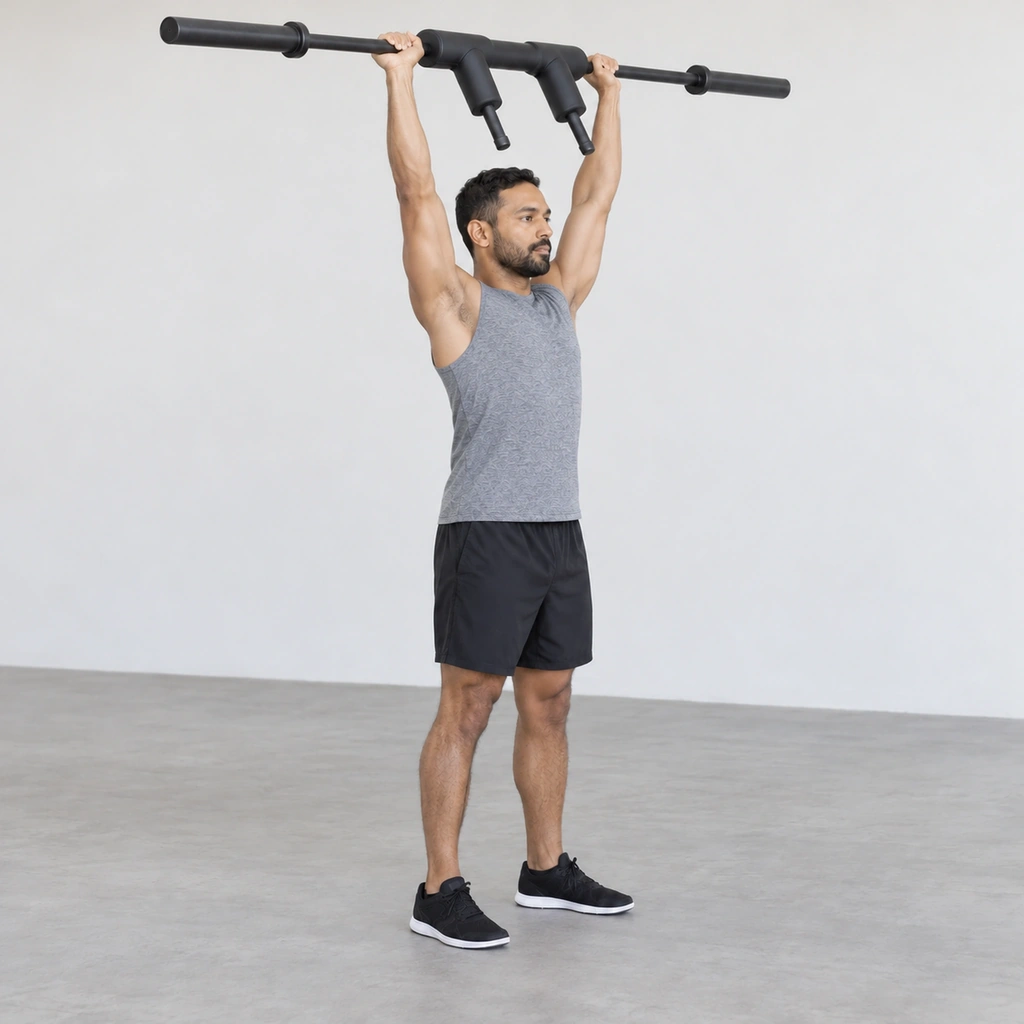 The same man with both arms locked out overhead holding the safety squat bar directly above his shoulders, hips and ankles, standing tall.