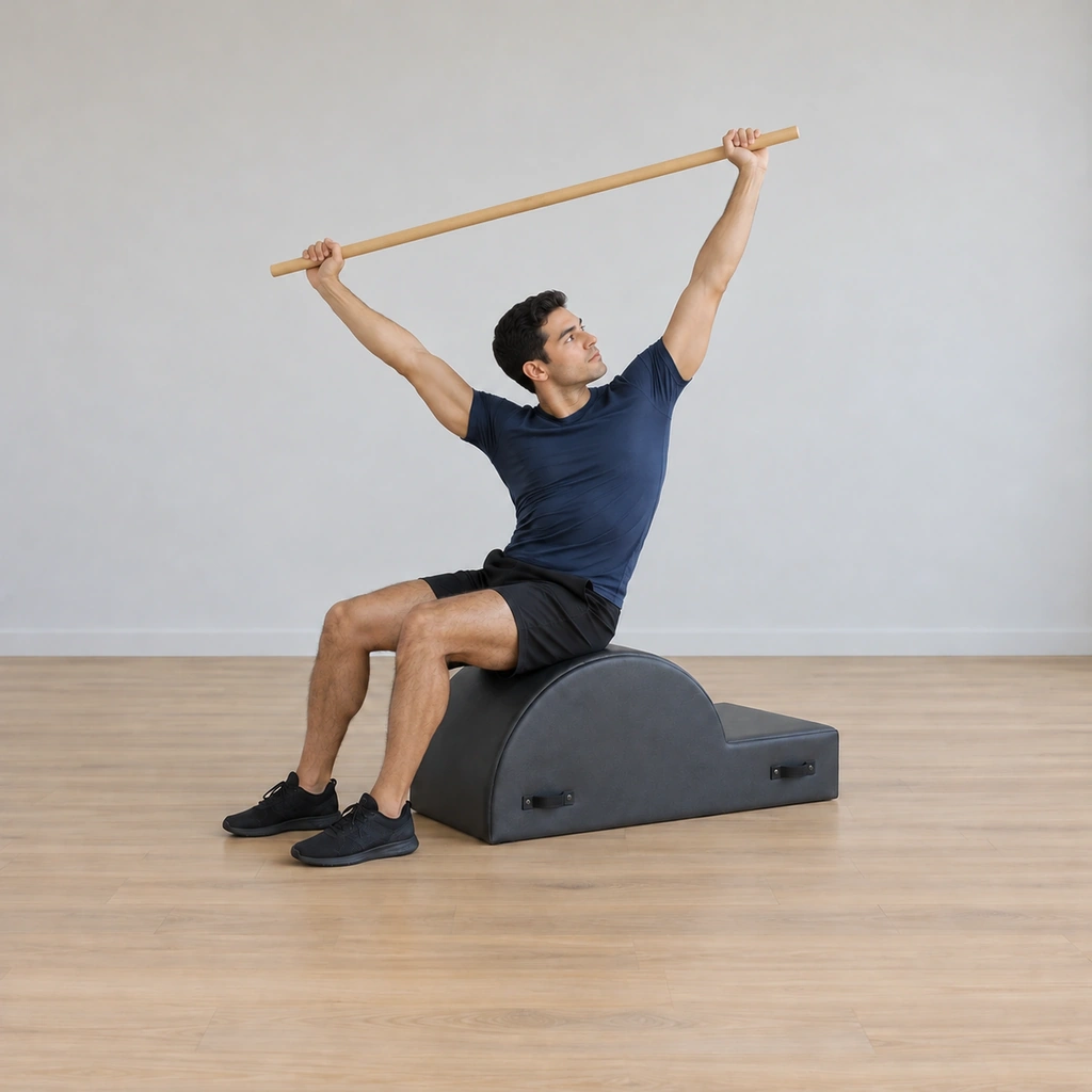 His torso is twisted and leaned back toward the rear corner of the barrel, chest rotated open toward the ceiling, the pole still wide overhead, hips unmoved.
