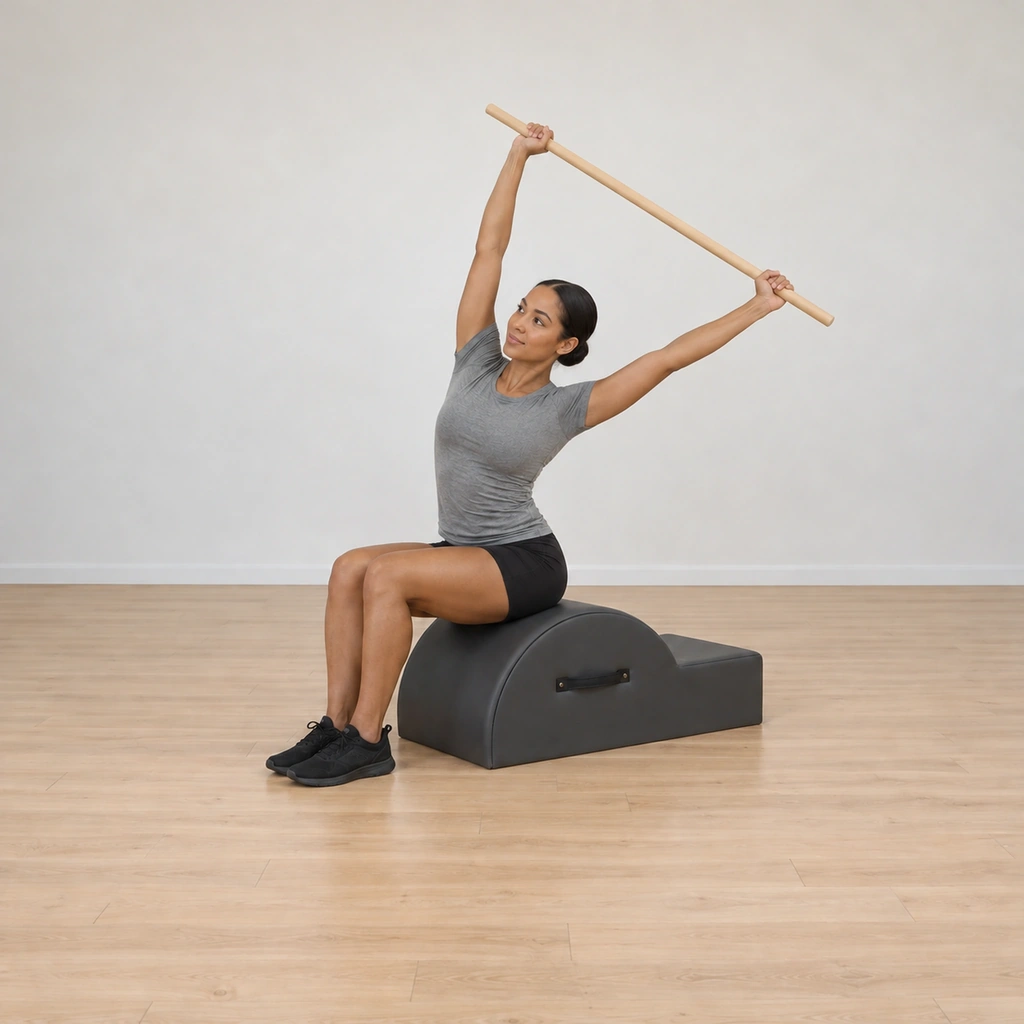 Her torso arcs up and over toward one side in a tall crescent, both sides of the waist kept long, the pole still wide overhead, hips unmoved.