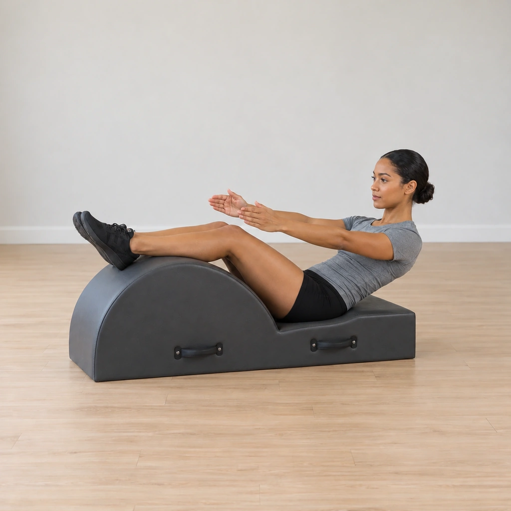 Her upper body lowers back toward the mat while her legs stay reaching in one place on the barrel, the teaser shape folding at the waist.