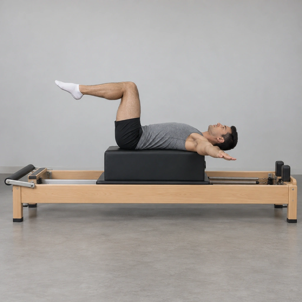 A man lying on a reformer's long box, knees bent in Tabletop, arms out to the sides, his upper back extending past the box's edge.