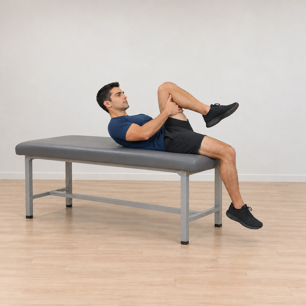 He is lowering his back toward the table one vertebra at a time, still holding his left knee up, his right knee bent and pointing toward the ceiling, his head coming down in line with his spine.
